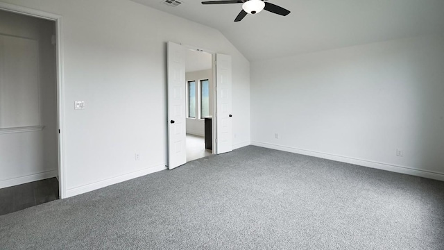 unfurnished bedroom featuring ceiling fan, vaulted ceiling, and dark colored carpet