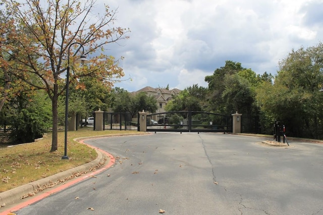 view of street featuring curbs, a gated entry, and a gate