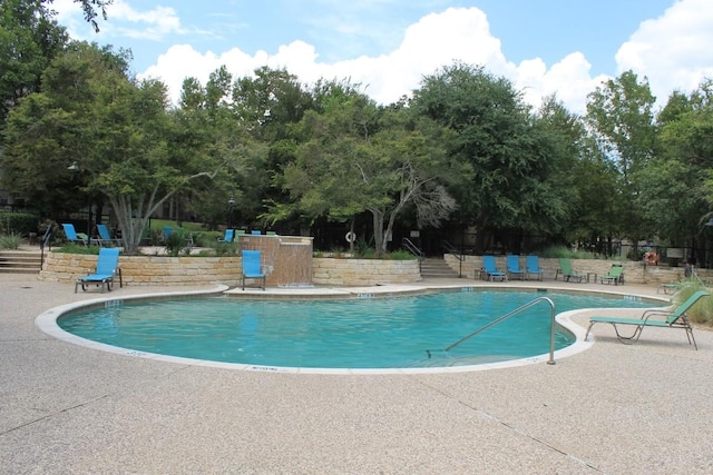 pool with a patio area and fence