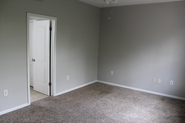 spare room featuring light carpet and baseboards