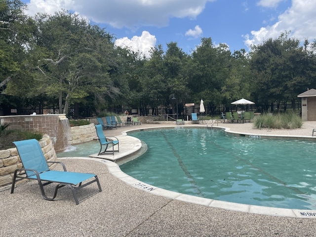 view of swimming pool with pool water feature and a patio