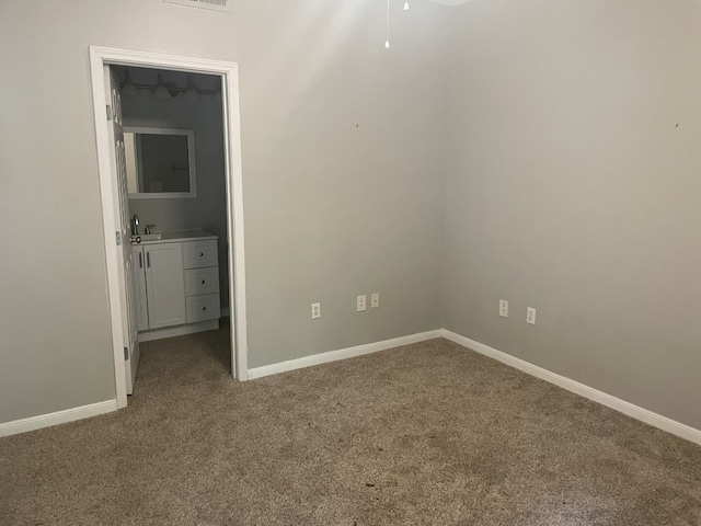 unfurnished bedroom featuring carpet, a sink, visible vents, and baseboards