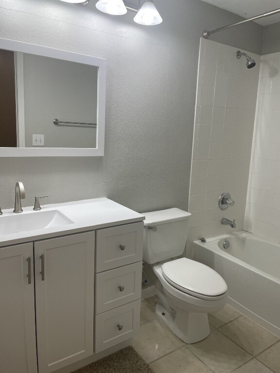 full bathroom featuring tiled shower / bath, vanity, toilet, and tile patterned floors