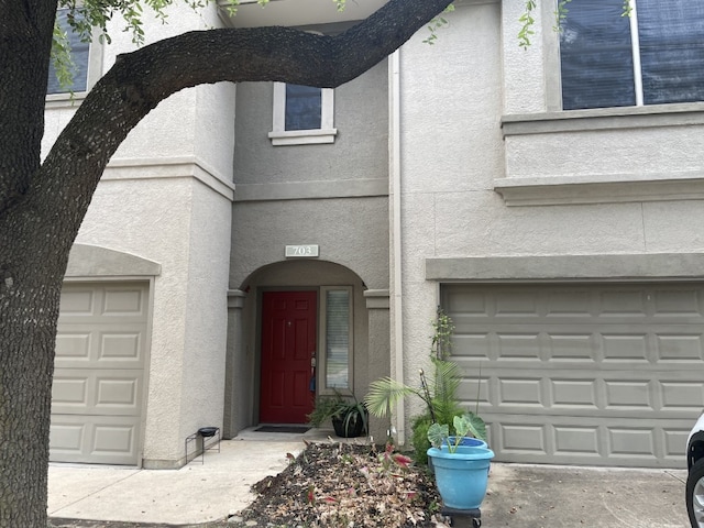 view of exterior entry featuring a garage and stucco siding