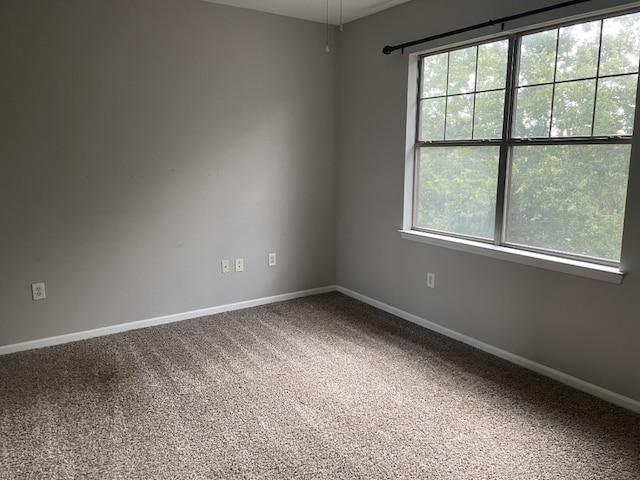 carpeted spare room featuring plenty of natural light and baseboards