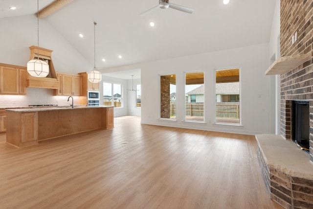 kitchen featuring light wood-type flooring, pendant lighting, a brick fireplace, and decorative backsplash