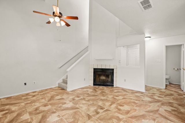 unfurnished living room featuring ceiling fan, light tile patterned floors, and a tile fireplace