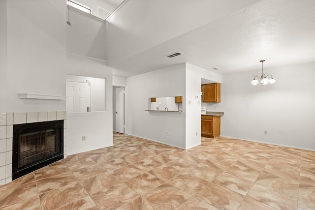 unfurnished living room featuring a tiled fireplace, a notable chandelier, and light tile patterned flooring