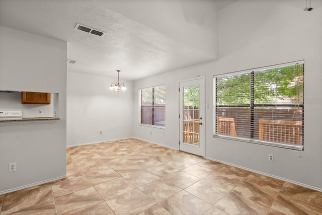 tiled empty room with a chandelier and a textured ceiling