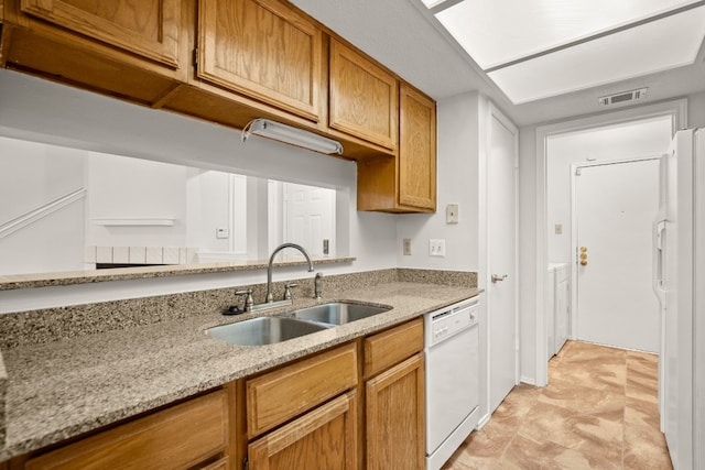 kitchen featuring white appliances, light tile patterned floors, light stone counters, and sink