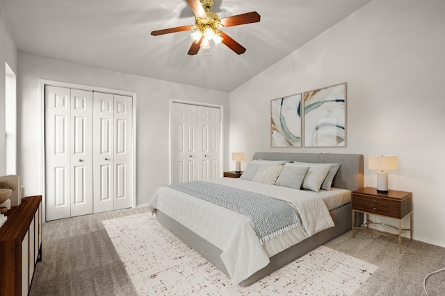 bedroom featuring multiple closets, vaulted ceiling, ceiling fan, and light colored carpet