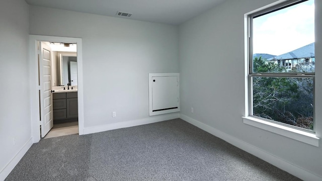 unfurnished bedroom featuring light carpet and ensuite bathroom