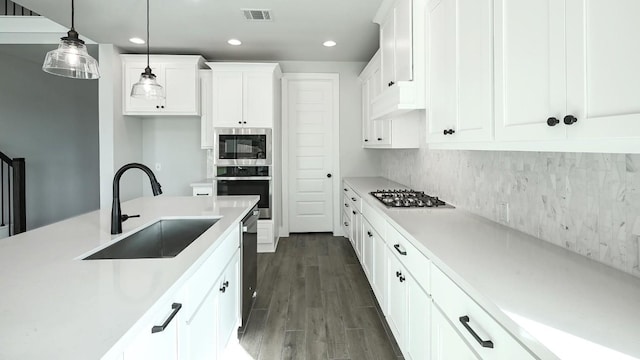 kitchen featuring pendant lighting, dark wood-type flooring, sink, appliances with stainless steel finishes, and white cabinetry