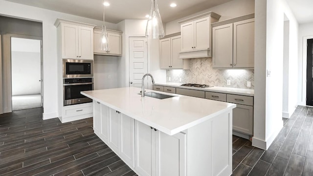 kitchen featuring backsplash, a kitchen island with sink, sink, and appliances with stainless steel finishes