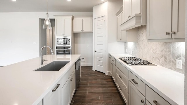 kitchen with decorative backsplash, stainless steel appliances, sink, pendant lighting, and white cabinets