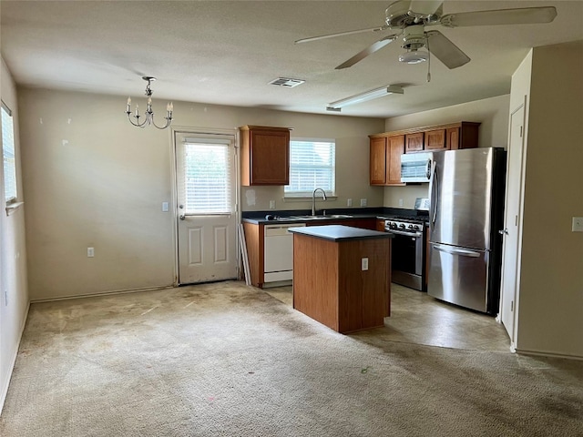 kitchen featuring a center island, stainless steel appliances, pendant lighting, light carpet, and ceiling fan with notable chandelier