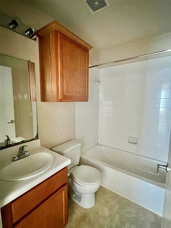 full bathroom with tiled shower / bath, vanity, and toilet