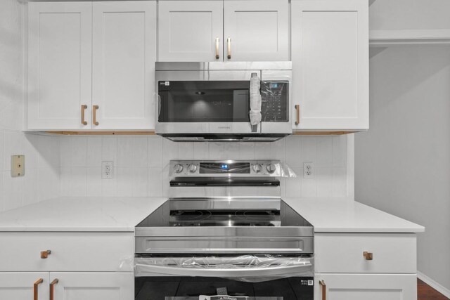 kitchen with appliances with stainless steel finishes, white cabinetry, and tasteful backsplash