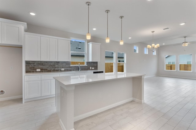 kitchen featuring white cabinetry, sink, a kitchen island, and ceiling fan with notable chandelier