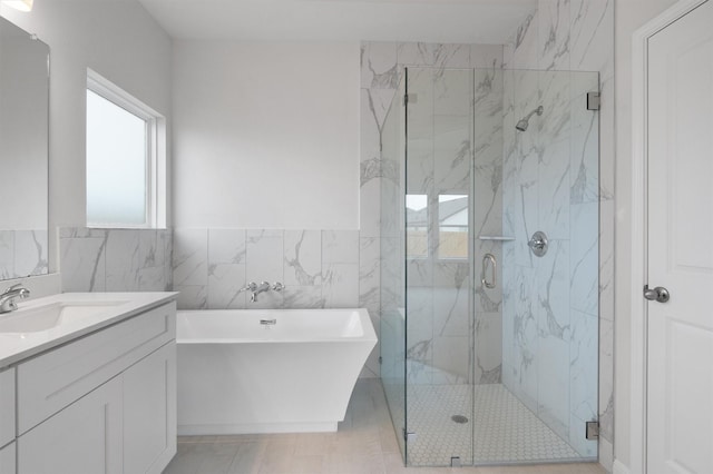 bathroom with vanity, tile walls, and shower with separate bathtub