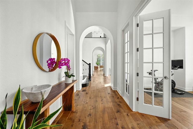 corridor with wood-type flooring and french doors