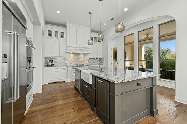 kitchen featuring white cabinetry, pendant lighting, an island with sink, and sink