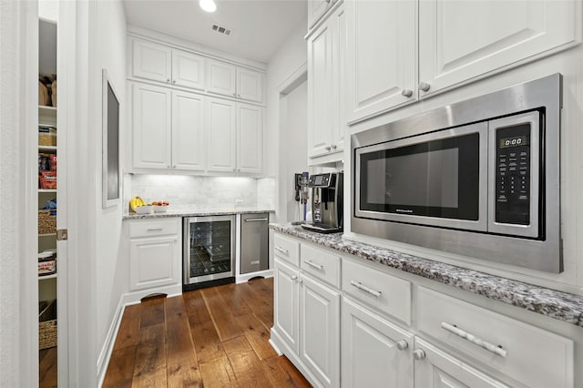 kitchen with white cabinets, beverage cooler, dark hardwood / wood-style flooring, light stone counters, and stainless steel microwave