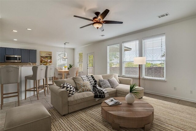 tiled living room featuring crown molding and ceiling fan