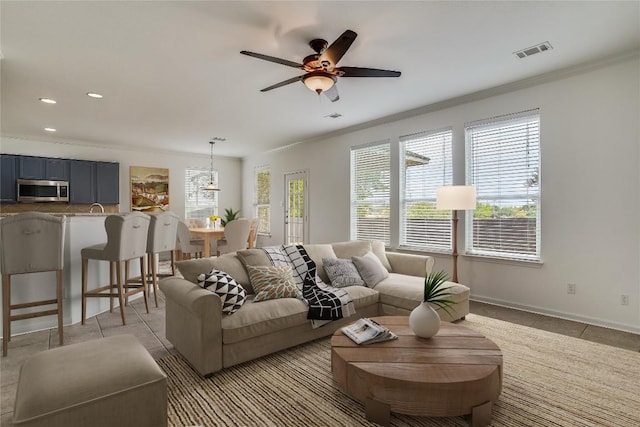 living room featuring ceiling fan, light tile patterned floors, and crown molding