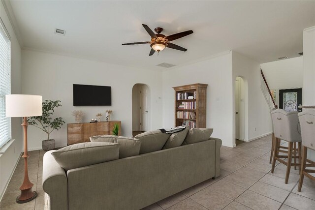 tiled living room with ornamental molding, ceiling fan, and a healthy amount of sunlight