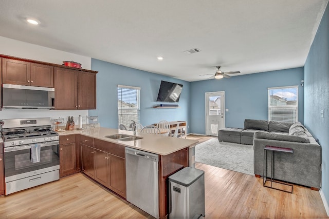 kitchen featuring light wood-type flooring, kitchen peninsula, sink, ceiling fan, and appliances with stainless steel finishes