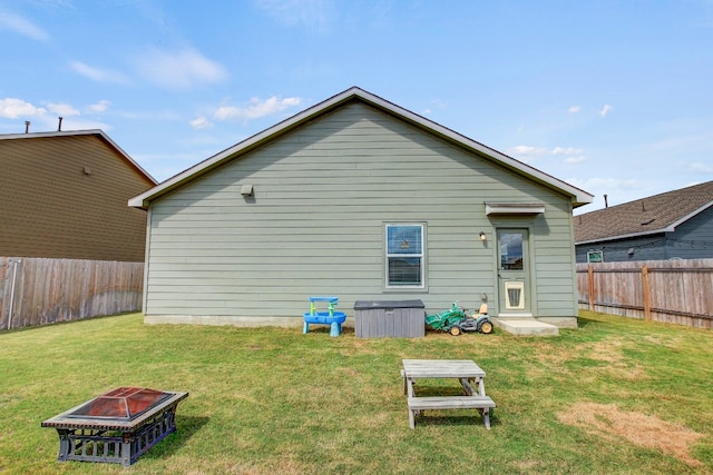 rear view of house with a fire pit and a yard