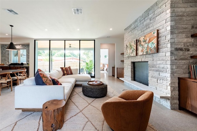 living area with expansive windows, a large fireplace, visible vents, and recessed lighting