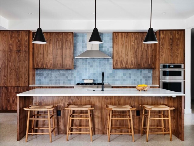 kitchen with decorative light fixtures, a large island, double oven, decorative backsplash, and a breakfast bar