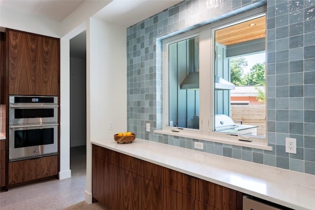 kitchen with light countertops, stainless steel double oven, modern cabinets, and decorative backsplash