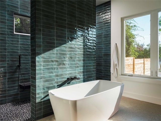 bathroom with a walk in shower, a soaking tub, tile walls, and baseboards