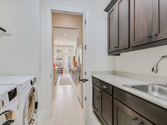 laundry area featuring cabinets, sink, light tile patterned floors, an inviting chandelier, and independent washer and dryer