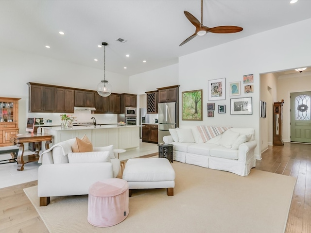 living room featuring light hardwood / wood-style floors, ceiling fan, and sink