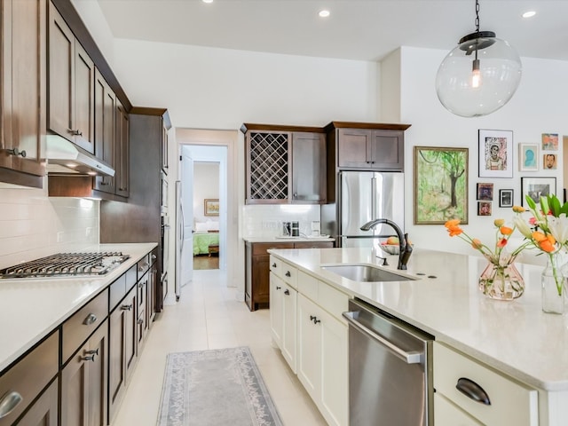 kitchen featuring sink, stainless steel appliances, backsplash, dark brown cabinets, and light tile patterned floors