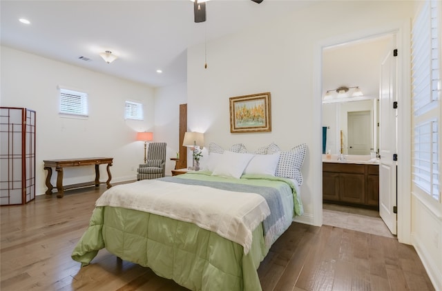 bedroom featuring ensuite bathroom, light hardwood / wood-style floors, multiple windows, and ceiling fan