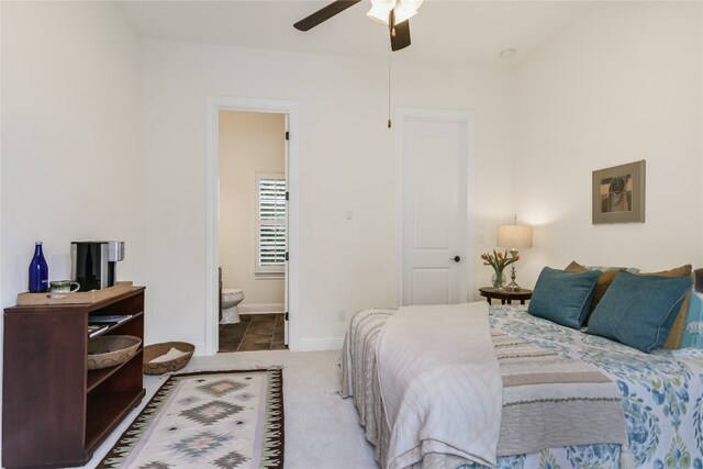 carpeted bedroom with ensuite bath and ceiling fan