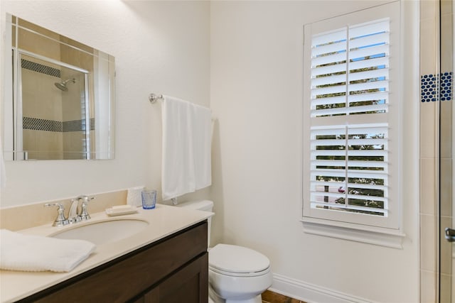 bathroom with vanity, toilet, and a shower with door