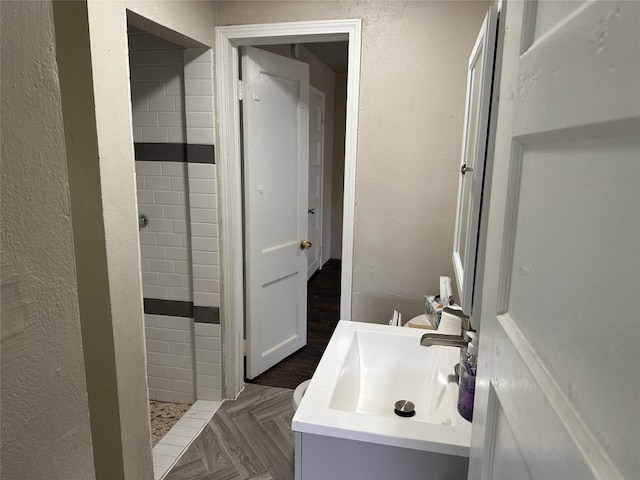 bathroom with vanity, parquet flooring, and tiled shower