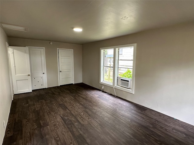 unfurnished bedroom featuring cooling unit and dark wood-type flooring