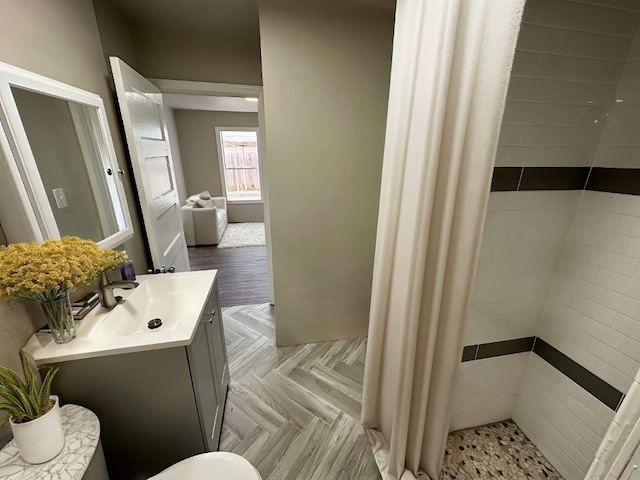 bathroom featuring a tile shower, parquet floors, and vanity