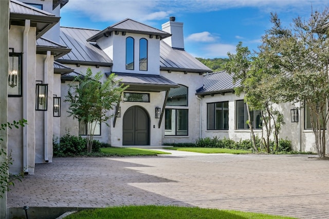 exterior space featuring a standing seam roof, a chimney, and metal roof