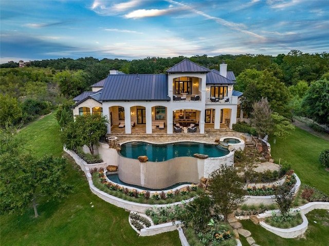 rear view of property featuring a standing seam roof, metal roof, a balcony, a chimney, and a patio area