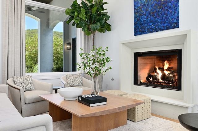 interior space with a lit fireplace and ceiling fan