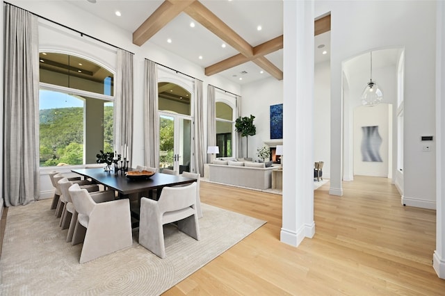 dining space with beam ceiling, a healthy amount of sunlight, coffered ceiling, and light wood-type flooring