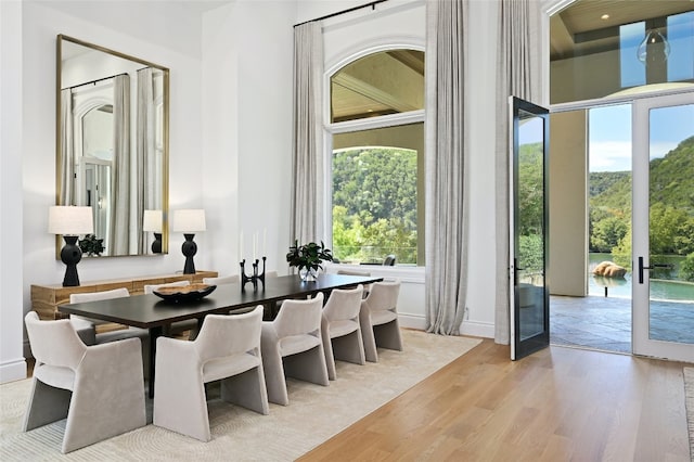 dining area with baseboards, light wood-type flooring, and french doors